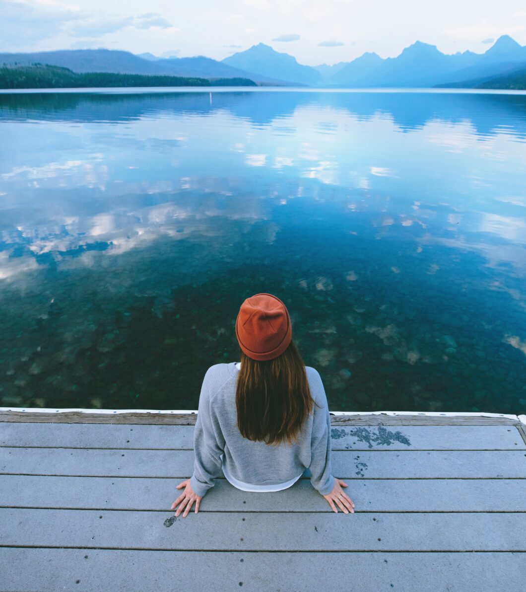donna seduta su un pontile guarda un lago, prima visita dallo psicologo