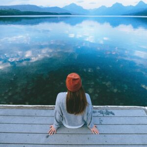donna seduta su un pontile guarda un lago, prima visita dallo psicologo