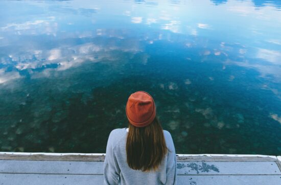 donna seduta su un pontile guarda un lago, prima visita dallo psicologo